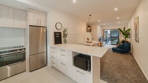 Et moderne køkken med indbyggede hårde hvidevarer, et spiseområde og en opholdsstue med sofa.