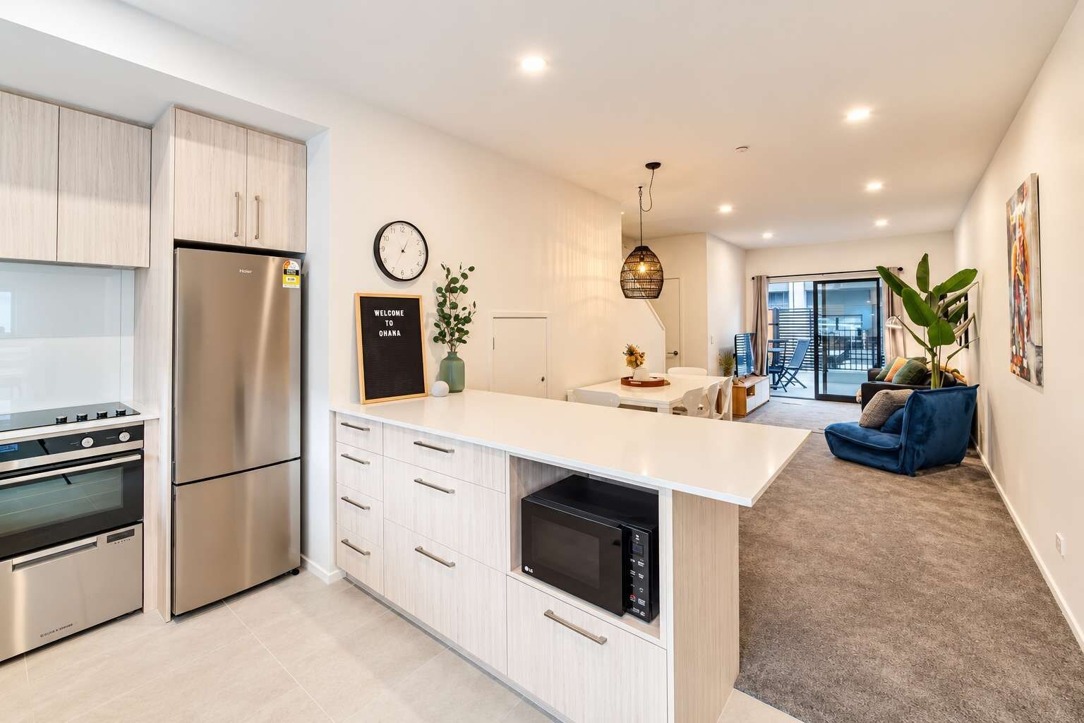 A modern kitchen with stainless steel appliances, a central island, and a dining area with a view to the outdoors.
