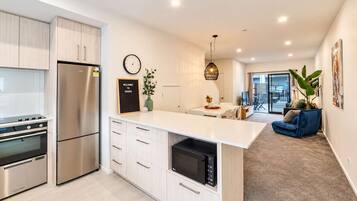 A modern kitchen with stainless steel appliances, a central island, and a dining area with a view to the outdoors.