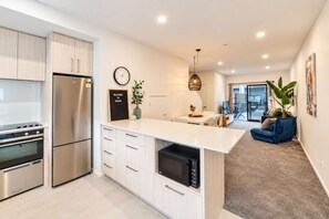 A modern kitchen with stainless steel appliances, a central island, and a dining area with a view to the outdoors.