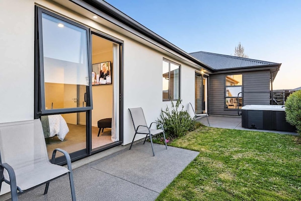 Une maison moderne dotée d’un patio, d’un jacuzzi et d’une pelouse bien entretenue.