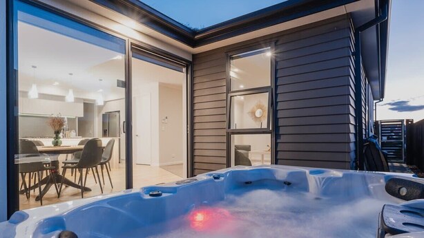 Un espace moderne aménagé à l’extérieur avec un jacuzzi et une porte vitrée donnant sur une salle à manger.