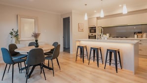 Une cuisine moderne dotée d’un îlot central, de tabourets de bar et d’un coin repas avec des chaises.