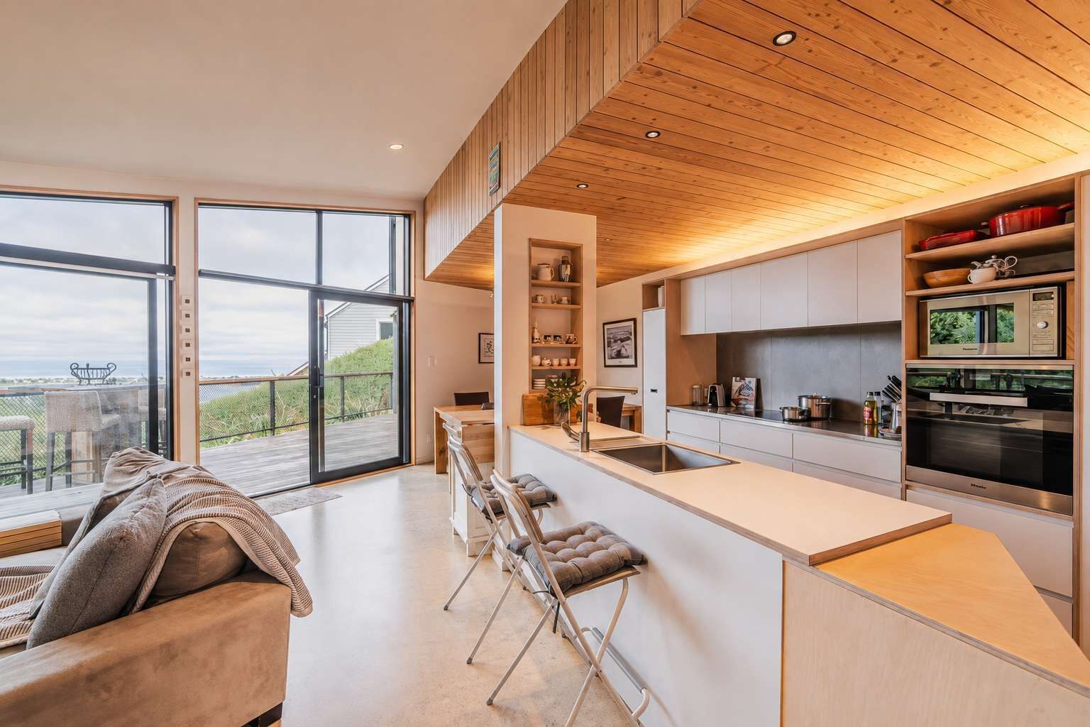 Una cocina moderna con una isla grande, electrodomésticos integrados y vistas al exterior.
