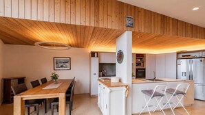 A modern kitchen with a central island, white cabinetry, and stainless steel appliances. - Ocean Views | 3BR Home with Hot Tub & Parking (Christchurch)