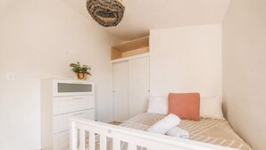 A bedroom with a bed, a dresser, a wardrobe, and a hanging light fixture. - Ocean Views | 3BR Home with Hot Tub & Parking (Christchurch)