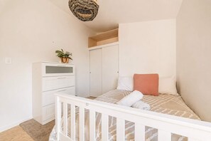 A bedroom with a bed, a dresser, a wardrobe, and a hanging light fixture. - Ocean Views | 3BR Home with Hot Tub & Parking (Christchurch)
