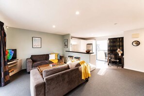 Ein modernes Wohnzimmer mit einer Couch, einem Couchtisch und einem Flachbildfernseher.