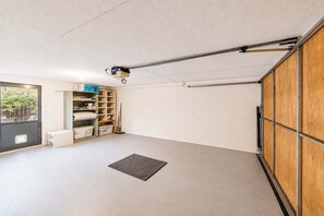Eine Garage mit Betonboden, einer Holztür und einem an der Decke befestigten Projektor.