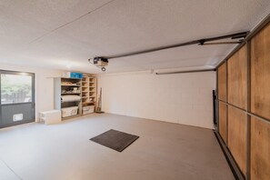Een garage met een betonnen vloer, een houten deur en een rek met opbergdozen.