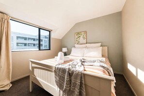 Ein Hotelzimmer mit einem Bett, einem Fenster, einer Lampe und einem Wandbild.