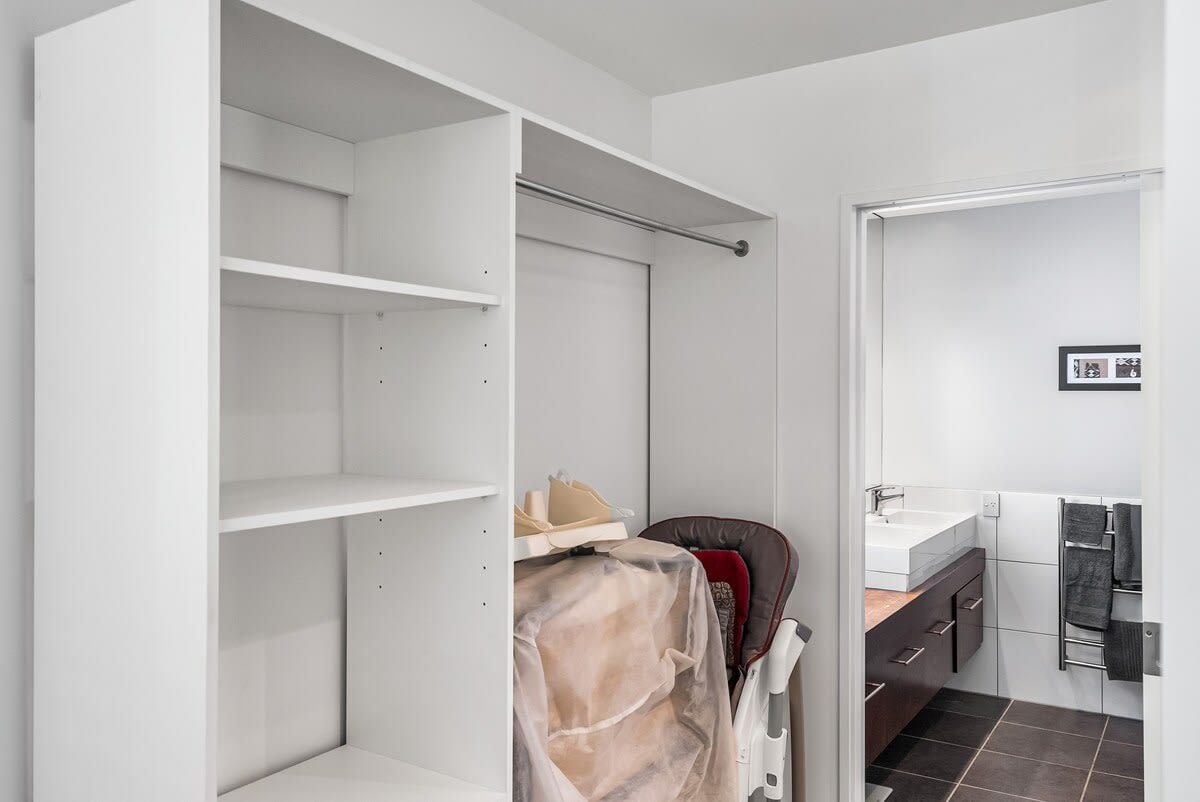 Un baño con un lavamanos blanco, piso de baldosas oscuras y un perchero.