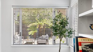 A window with horizontal blinds, a potted plant, and a bookshelf with books. - KaleidoNook | 3BR + Parking + Private Yard (Christchurch)