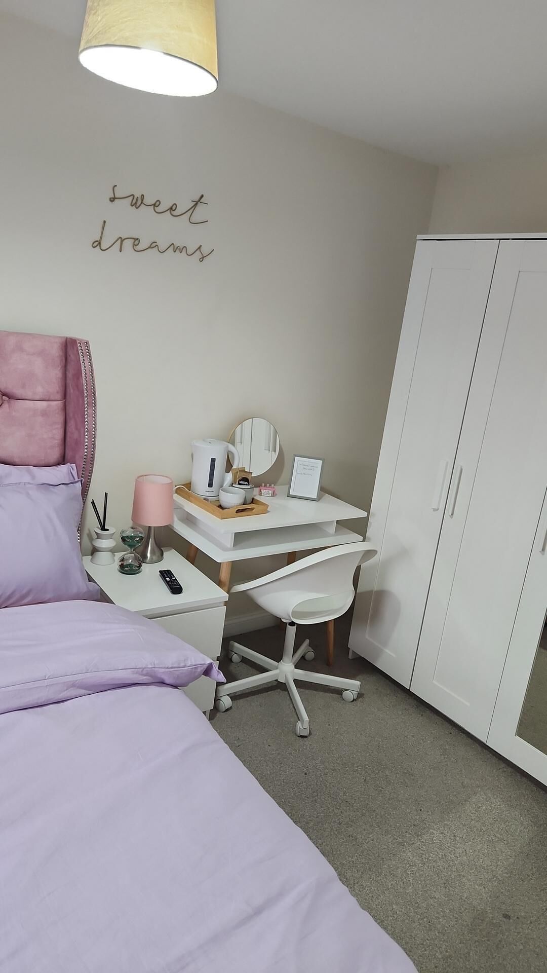 A bedroom with a bed, desk, chair, wardrobe, and a wall with 'sweet dreams' written on it.