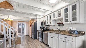 A modern kitchen with white cabinets, stainless steel appliances, and a granite countertop. - Stunning Oceanfront Getaway with Pool (Ocean City)