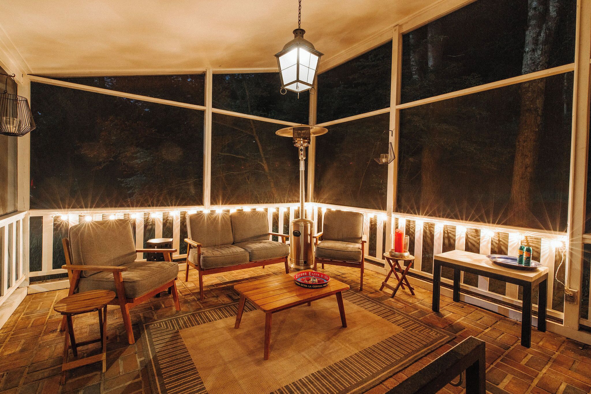 A cozy outdoor seating area with a wooden table, chairs, and a hanging lantern.