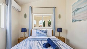 Une chambre à coucher avec un lit, deux tables de chevet, une fenêtre et un tableau au mur.