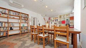Une bibliothèque avec des étagères en bois, une table à manger avec des chaises et un sol à motifs.