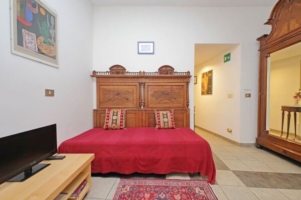 A room with a bed, a TV on a stand, a wooden cabinet, and a framed picture on the wall. - Cavour - Large and comfortable apartment for 6 close to the Coloseum (Roma)
