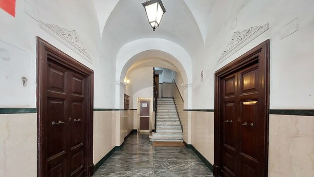 Un couloir doté d’un sol en marbre, de portes en bois et d’un plafond en arc de cercle.