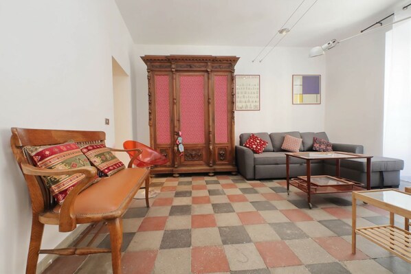 A living room with a checkered floor, a sofa, a wooden chair, a cabinet, and a table. - Cavour - Large and comfortable apartment for 6 close to the Coloseum (Roma)