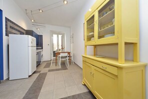 Une cuisine compacte avec un réfrigérateur blanc, un lave-linge, un meuble jaune et un coin repas comprenant une table et des chaises.