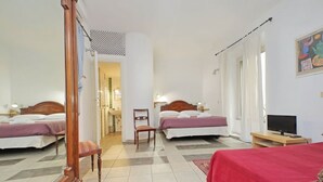 Une chambre d’hôtel avec deux lits, une chaise en bois, un téléviseur et une couverture rouge.