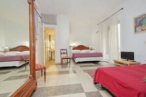 Ein Hotelzimmer mit zwei Betten, einem Holzstuhl, einem Fernseher und einer roten Bettdecke.
