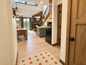 Een moderne keuken met een houten trap, een eethoek met uitzicht en een open haard.