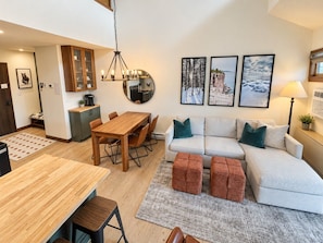 Un salon moderne avec une table à manger en bois, un ensemble de canapés et un coin café.