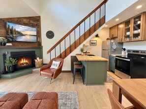 Una sala de estar moderna con chimenea, un comedor con mesa de madera y una cocina con estufa.