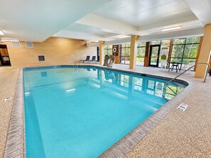 Une piscine intérieure à l’eau claire, entourée de chaises longues et d’un espace de repos abrité.