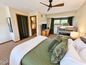 Une chambre d’hôtel avec un grand lit, un bureau, une télévision et une fenêtre avec des rideaux.