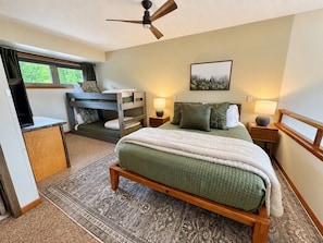 A bedroom with a bed, a desk, a chair, a ceiling fan, and a window with curtains. - Beautiful Mountainview Top Floor Loft | Ski-in/out (Lutsen)