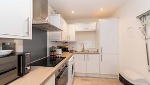 A compact kitchen with a microwave, toaster, sink, and a washing machine.