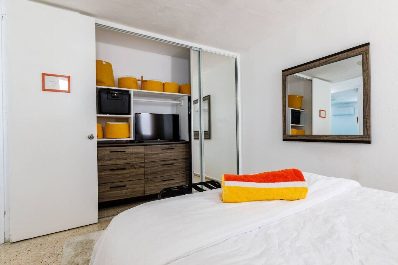 A bedroom with a bed, a wardrobe, and a mirror.