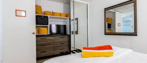 A bedroom with a bed, a wardrobe, and a mirror.