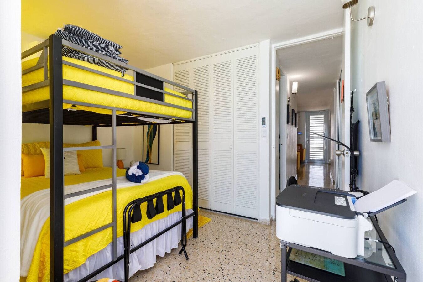 A bunk bed room with a desk and chair, a closet with sliding doors, and a door leading to another room.