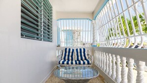 Ein Eckzimmer mit Glastisch, gestreifter Couch und Blick durch ein vergittertes Fenster.