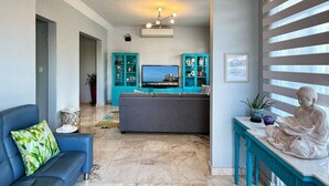 A living room with a sofa, a television, a statue, and a blue cabinet.