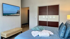 A hotel room with a bed, a bench, a wardrobe, and a TV on the wall.