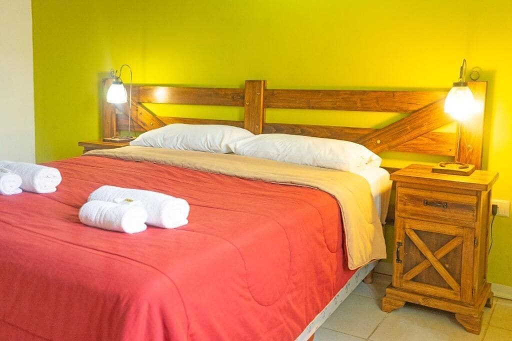 A bed with a wooden headboard, two bedside lamps, and a wooden nightstand with a drawer.