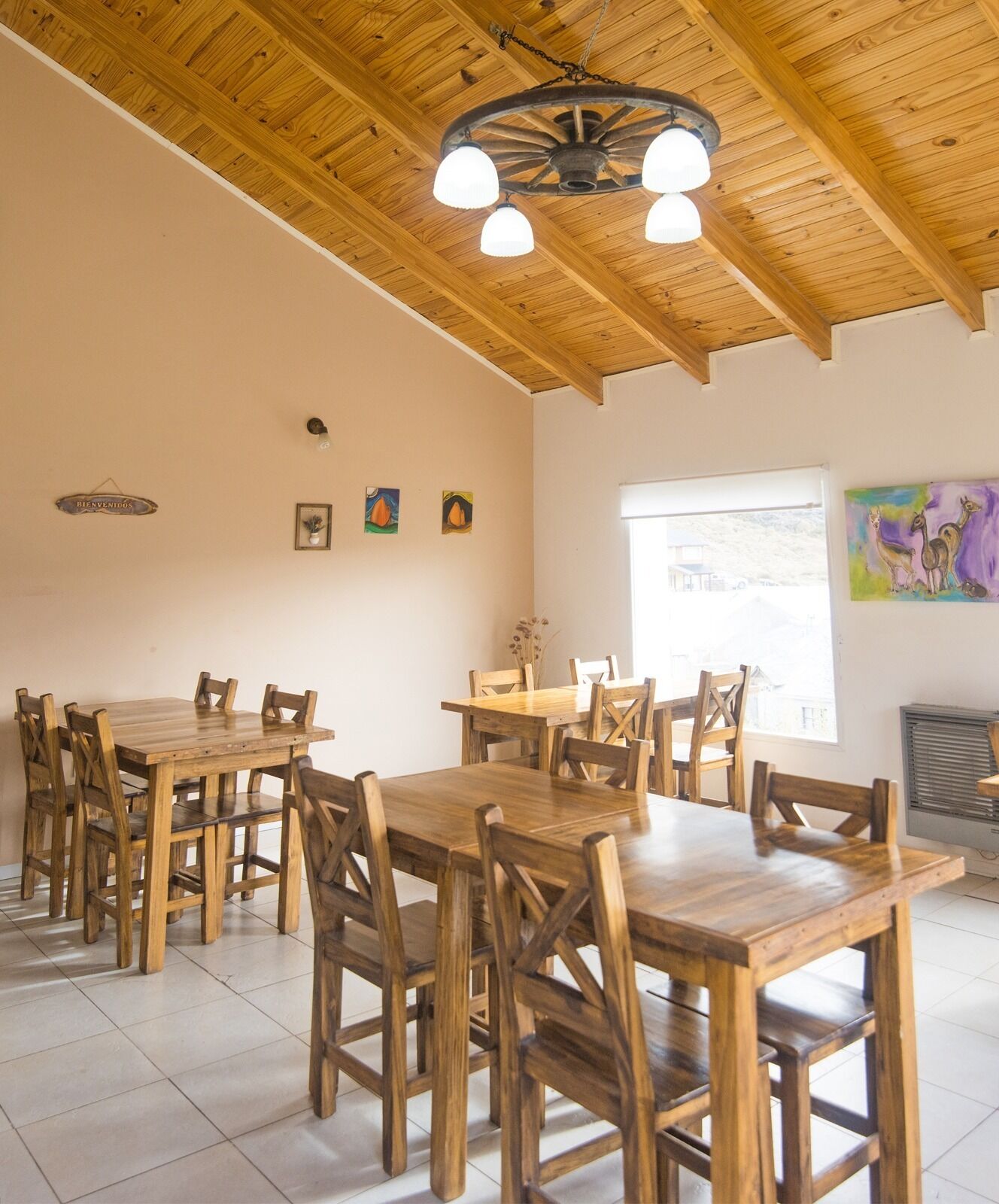 A dining area with wooden tables and chairs, a ceiling fan, and artwork on the walls.