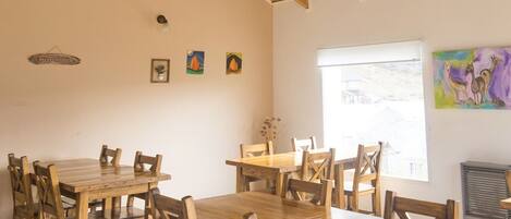 A dining area with wooden tables and chairs, a ceiling fan, and artwork on the walls.
