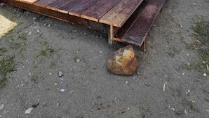 Une cabane moderne en bois, dotée d’une grande terrasse, d’une porte d’entrée en verre et offrant une vue sur le paysage environnant.