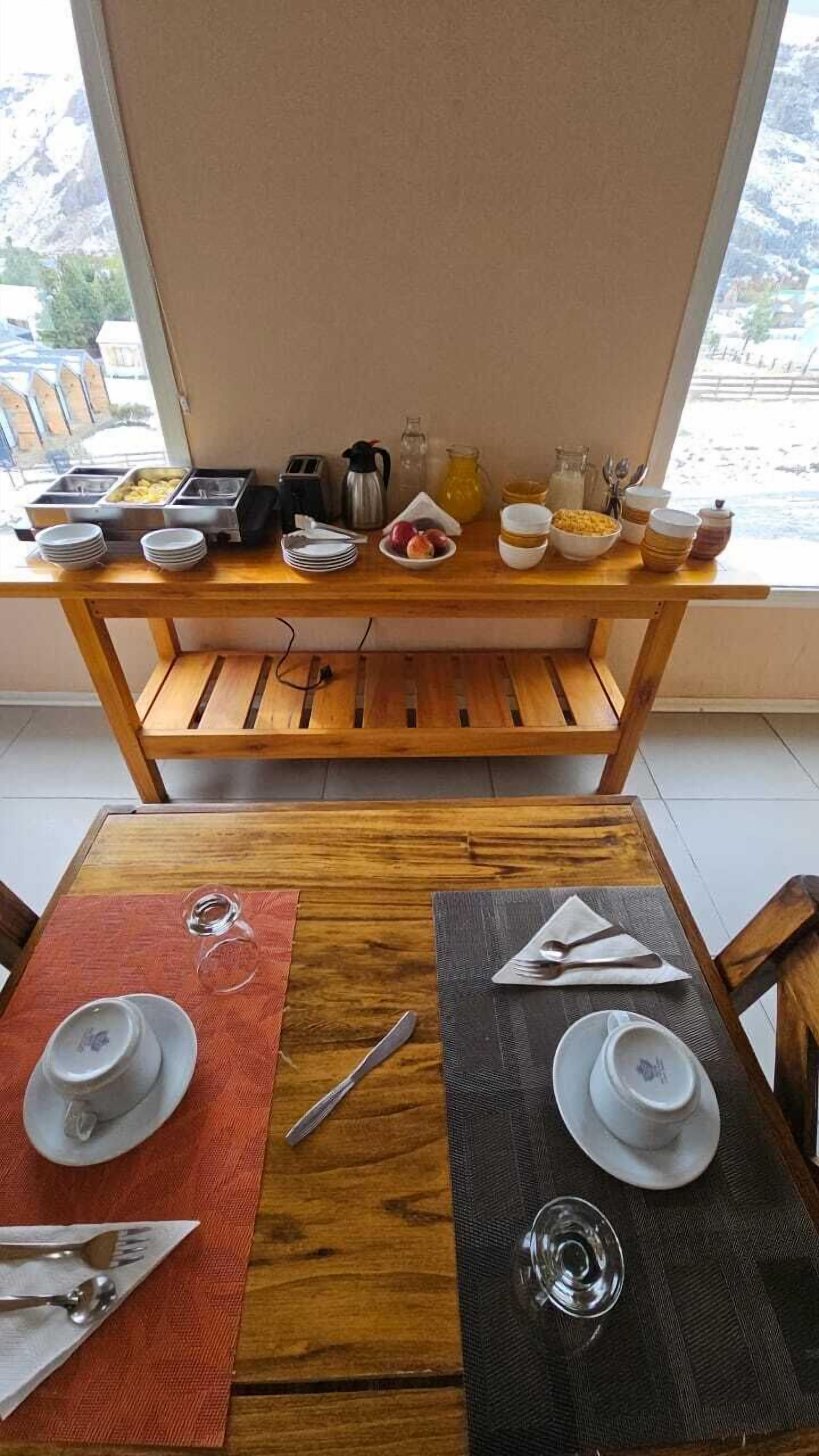 En frukostplats med ett träbord, två stolar och en frukostbuffé med olika sorters mat och tillbehör.