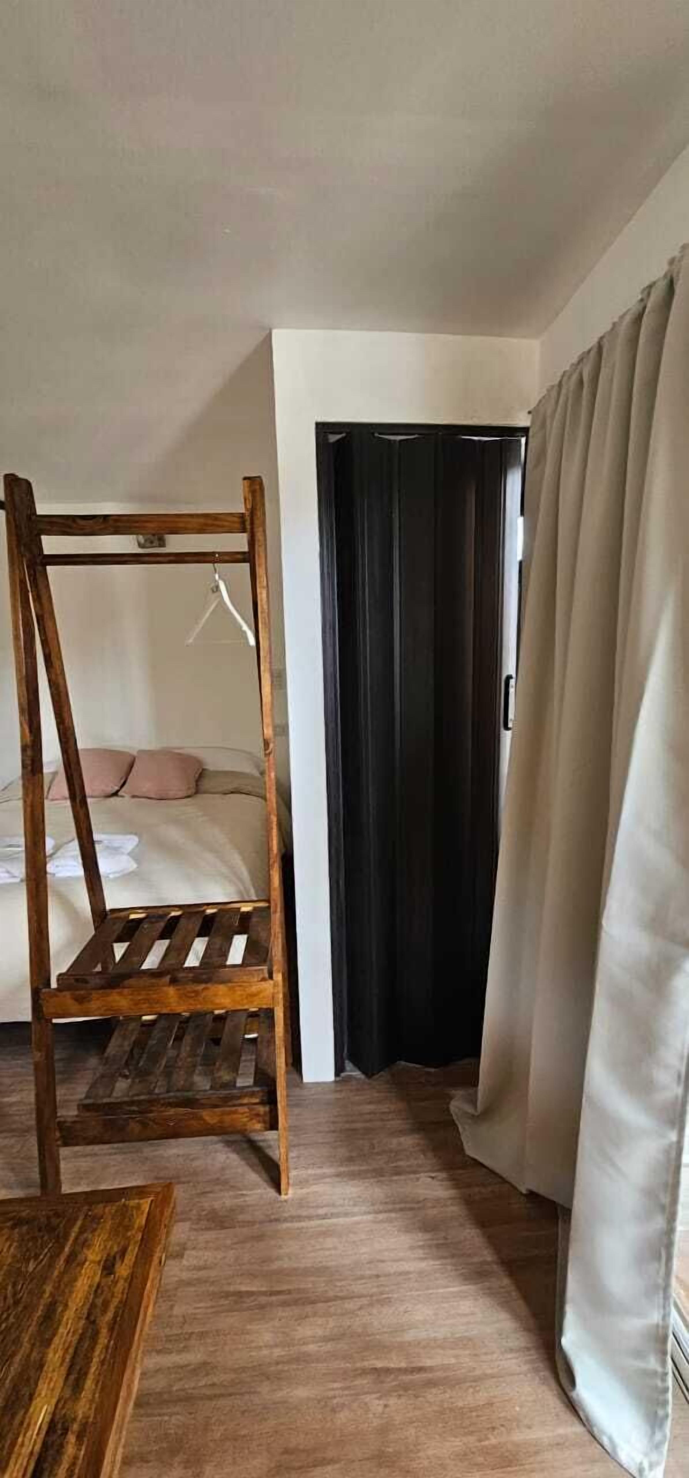 A bedroom with a wooden four-poster bed, a dark door, and a curtain.