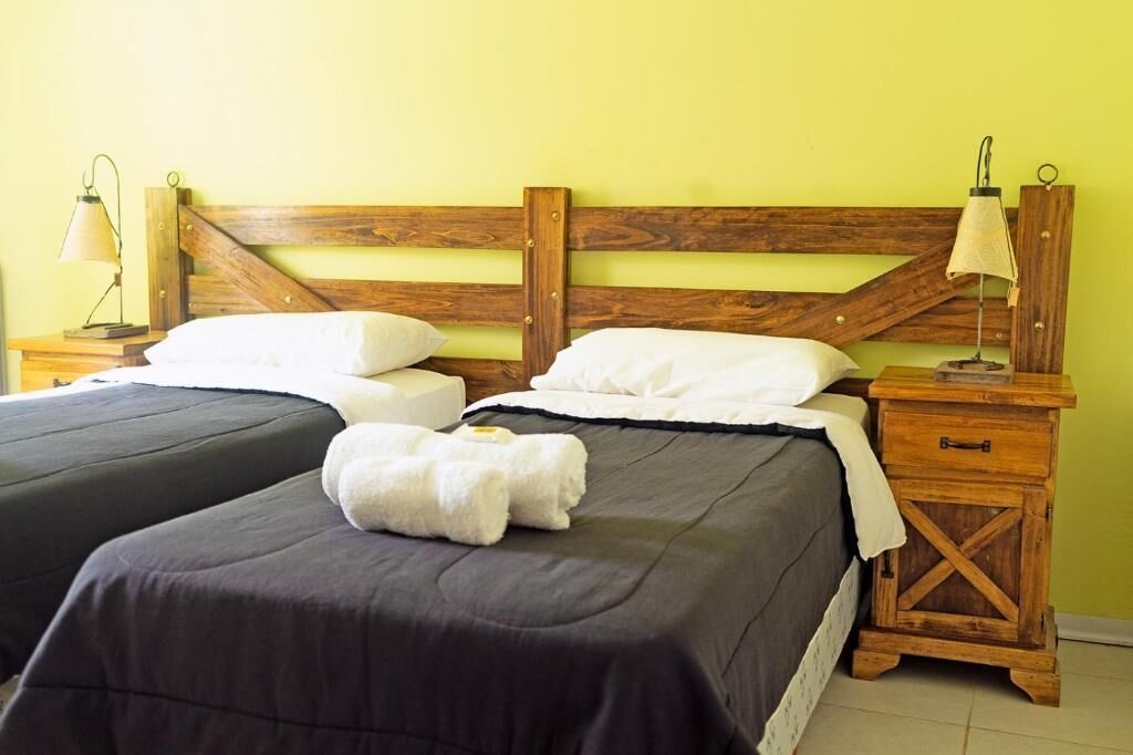 A double bed with a wooden headboard, two bedside tables with lamps, and a pair of white towels on the bed.