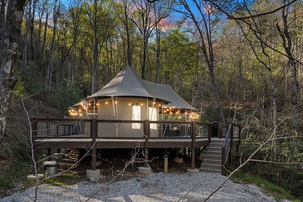 As dusk settles over the mountains, Lost Creek glows warmly beneath a canopy of trees — string lights dancing along the wraparound deck as the forest comes alive with the sounds of the night.