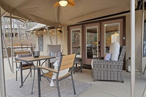 An outdoor patio with a table and chairs, a wicker sofa, and a ceiling fan. - Safari Tent (Bryson City)